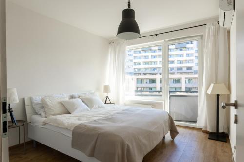 1 dormitorio con cama blanca y ventana grande en Quiet & Cozy Apartment Old Town - free underground parking, en Košice