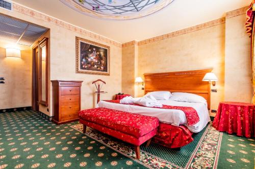 um quarto de hotel com uma cama e uma cadeira vermelha em Hotel Cristallo em Sestriere