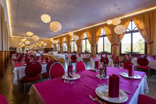 un comedor con mesas y sillas rosas y ventanas en Hotel Salegg, en Siusi