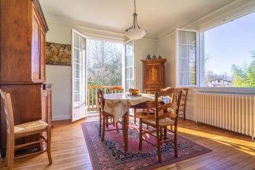 une salle à manger avec une table, des chaises et des fenêtres dans l'établissement Uharte, à Uhart-Cize