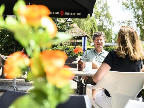Ein Mann und eine Frau sitzen an einem Tisch in einem Café im Freien in der Unterkunft Recreatiepark De Lucht in Renswoude