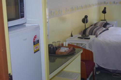 a room with a bed and a table with a microwave at Halls Gap Tavern in Halls Gap