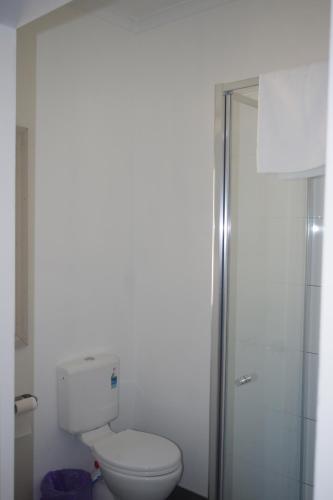 a white bathroom with a toilet and a shower at Halls Gap Tavern in Halls Gap