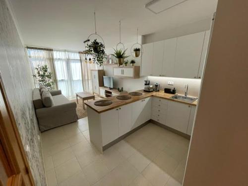 a kitchen with white cabinets and a couch in a room at Apartamento en Boiro - Colores del Barbanza Verde in Boiro