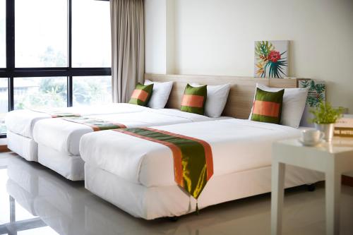 two large beds in a room with a large window at The Plimplace Hotel in Bang Su
