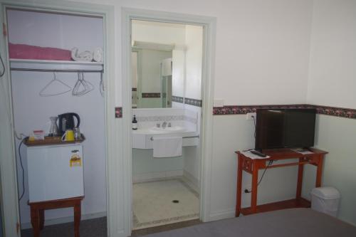 a room with a bathroom with a sink and a television at Halls Gap Tavern in Halls Gap