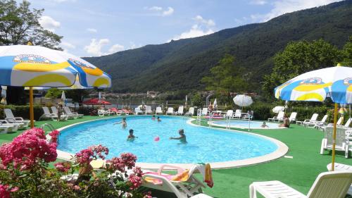 a pool with people in it with mountains in the background at Camping al Lago in Tarzo