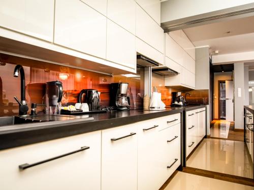 a kitchen with white cabinets and a black counter top at Prezydencki Apartamenty z widokiem na morze in Jarosławiec