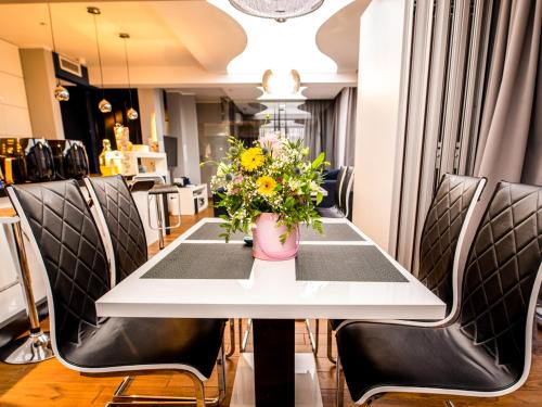 a table with chairs and a vase of flowers on it at Prezydencki Apartamenty z widokiem na morze in Jarosławiec