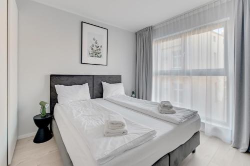 a white bedroom with a large bed with towels on it at Comfort Apartments Grano Residence in Gdańsk