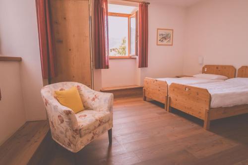 a bedroom with a bed and a chair and a chair at Agritur Ca' de Mel in Fiavè