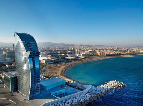 a tall building next to a beach and the ocean at Mar Bella Beach Apartments in Barcelona