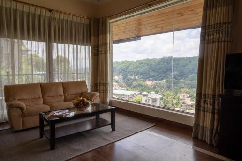 a living room with a couch and a large window at Kings Ridge Kandy in Kandy