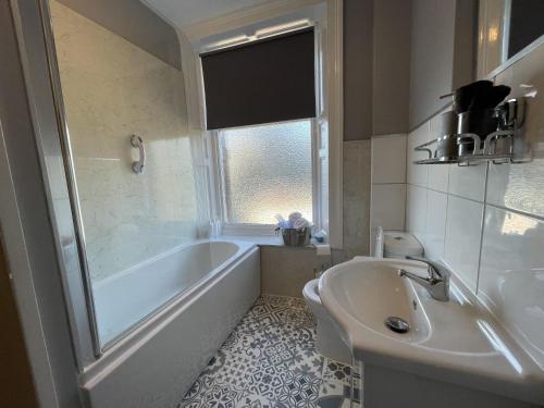 un bagno bianco con vasca e lavandino di Skiddaw View a Keswick