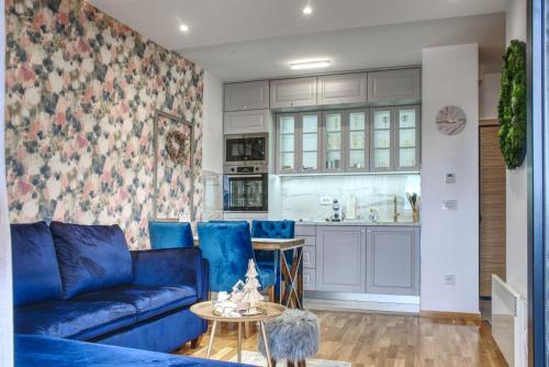 ein Wohnzimmer mit einem blauen Sofa und einer Küche in der Unterkunft Zlatibor SKAJ&SPA in Zlatibor