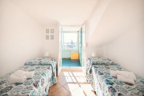 2 camas en una habitación con ventana en Porto Sole Apartment by Wonderful Italy, en San Remo