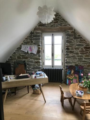Cette chambre mansardée dispose d'une table et d'un mur en pierre. dans l'établissement villa santa lucia, à Pornic
