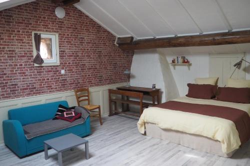 a bedroom with a bed and a couch and a brick wall at Chambres d'hôtes du Ruisseau d'Argent in Archettes