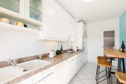 une cuisine blanche avec un évier et une table dans l'établissement ELEGANCE YourHostHelper, au Cannet