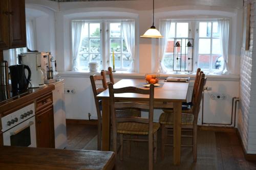 eine Küche mit einem Holztisch mit Stühlen und einer Tableasteryasteryasteryastery in der Unterkunft Doktors Hus in Oldenswort