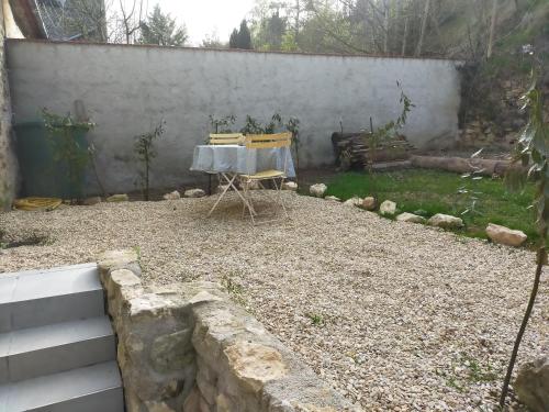 a table and chairs in a backyard with a wall at Logement entier dans village calme in Guillerval