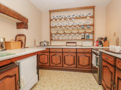 a kitchen with wooden cabinets and plates on the wall at Beckside Farm in Millom
