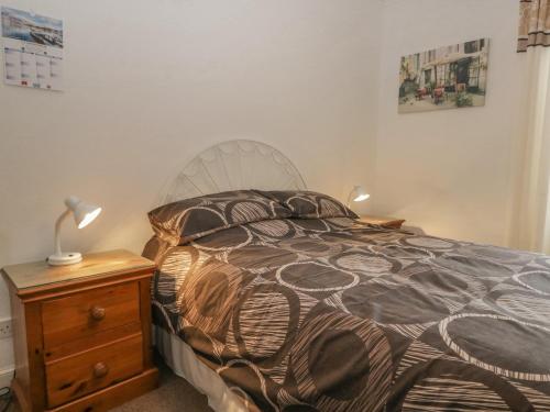 a bedroom with a bed and a table with a lamp at Beckside Farm in Millom