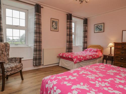 a bedroom with two beds and a chair at Beckside Farm in Millom