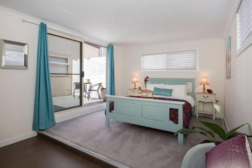 een slaapkamer met een bed en uitzicht op een balkon bij Swanway family holiday home - 15 min walk to beach, seconds to lake in Culburra Beach