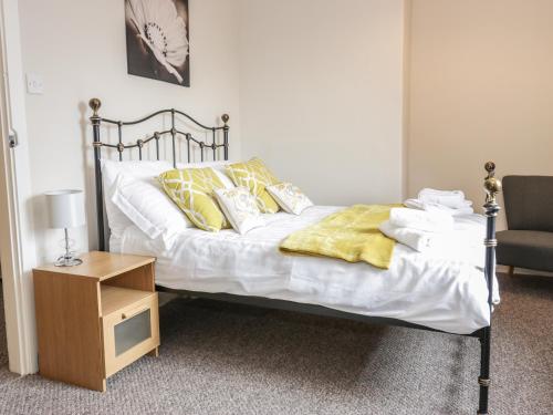 1 cama con sábanas blancas y almohadas amarillas junto a una silla en Sea Lily en Cheswick