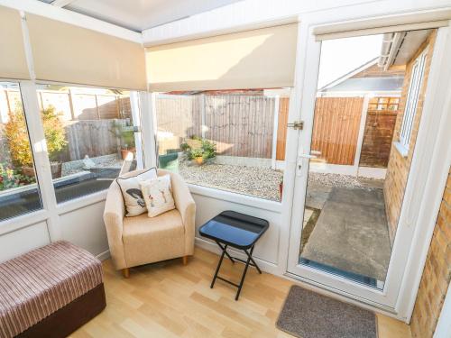 a screened in porch with a chair and sliding glass doors at Bumble Bee Cottage in Skegness