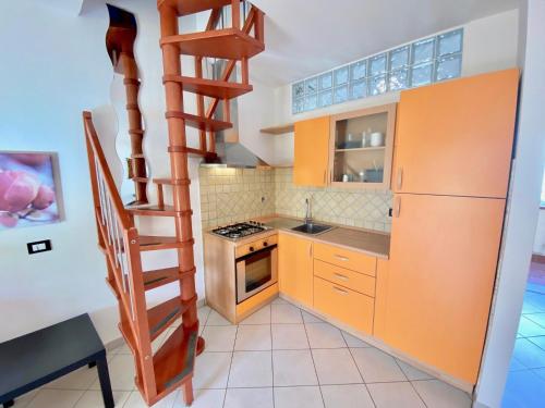 eine Küche mit orangefarbenen Schränken und einer Wendeltreppe in der Unterkunft Bilocale Via del Mare in Marina di Bibbona