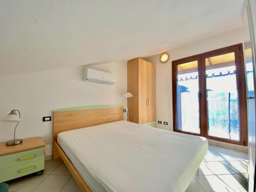 una camera con un letto bianco e una finestra di Bilocale Via del Mare a Marina di Bibbona