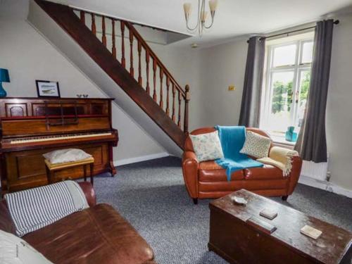 a living room with a piano and a couch and chairs at Corner Cottage, Swansea in Reynoldston