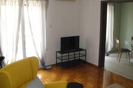 sala de estar con sofá amarillo y TV en Illisia Roof Apartment, en Atenas