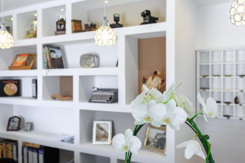 a vase with white flowers in front of a shelf at Hotel Villa Fernanda in Massa Lubrense