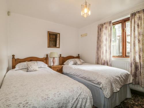 2 Betten in einem weißen Zimmer mit Fenster in der Unterkunft Pond End Cottage in Morland