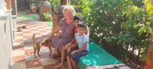 a woman and two children sitting on a bench with a dog at Ambadi's villa -Lake view resort in Pallipuram