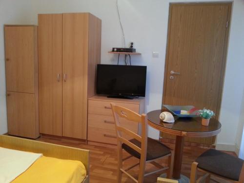 Habitación pequeña con mesa, TV y dormitorio. en Apartments Previšić, en Cavtat