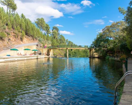 a river with a bridge in the background at Monte das Cerejas in Montes da Senhora