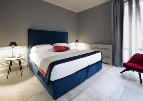 a bedroom with a large bed and a red chair at Palazzo Cornalia in Milan