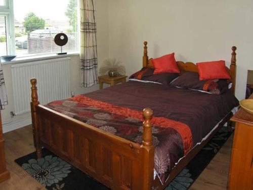 una camera da letto con un grande letto in legno con cuscini rossi di Sunnyside Cottage a Skegness