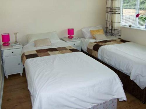 2 letti in una camera da letto con candele rosa sui tavoli di Sunnyside Cottage a Skegness