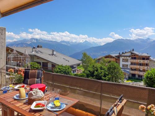 a table on a balcony with a view of mountains at Studio Jeanne D'Arc Apt- E-36 by Interhome in Crans-Montana