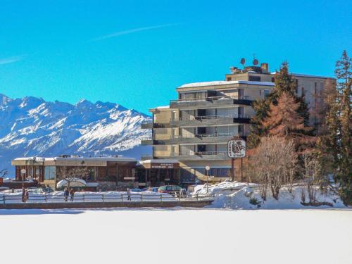 a large building with a snow covered mountain in the background at Studio Jeanne D'Arc Apt- E-36 by Interhome in Crans-Montana