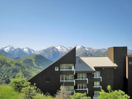 a black building with mountains in the background at Apartment Balcon d'Huez by Interhome in L'Alpe-d'Huez
