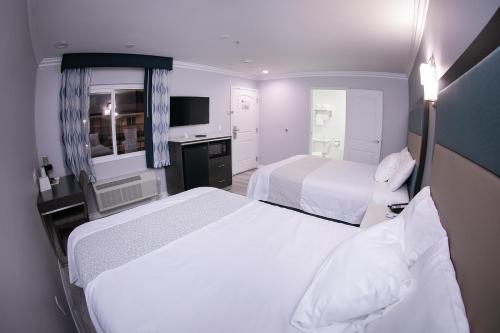 a hotel room with two beds and a television at Travelodge Inn & Suites by Wyndham West Covina in West Covina