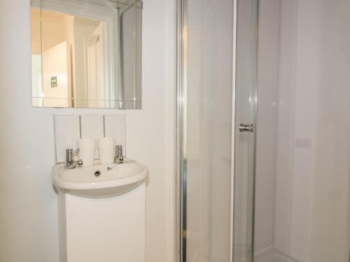 a white bathroom with a sink and a shower at Sea Breezes in Newquay