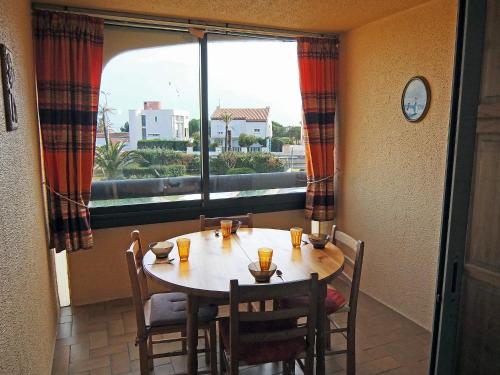 une table et des chaises dans une pièce avec une grande fenêtre dans l'établissement Apartment Les Mas de La Mer-7 by Interhome, à Saint Cyprien Plage