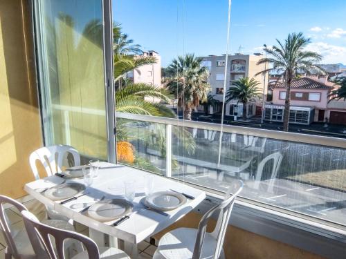 une table et des chaises blanches devant une fenêtre dans l'établissement Apartment Les Albères by Interhome, à Saint Cyprien Plage